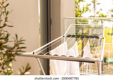 Hanging laundry on balcony on the drying rack opposite sea and palm trees view at sunset sunshine