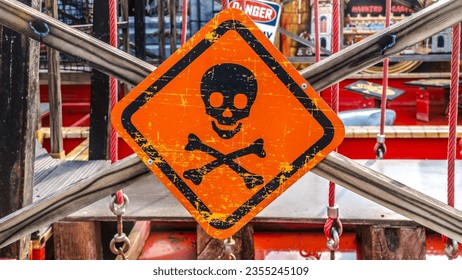 Hanging metal sign toxic with scull and bones over orange.