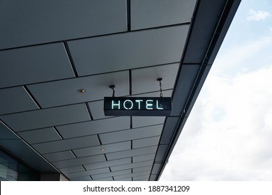 Hanging Neon Hotel Sign And Cloudy Sky.