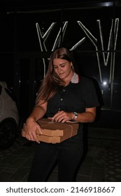 Hanging out. Young casually woman on a parking site eating pizza at night. Lifestyle millennial gen z generation