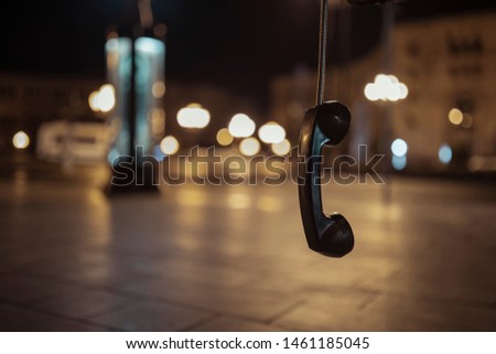 Hanging Public telephone at night , ear phone,  pay phone. hanging phone.
Feelings - separation, emptiness, loneliness, resentment. bokeh background