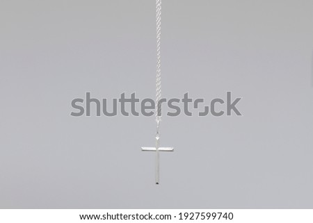 
hanging Silver cross with chain on grey background 