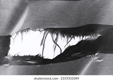 hanging teared rag spread isolated on black background , can use like a background or any texture. hole in the tissue. Unbleached beige fabric with torn stitch, hole and loose threads