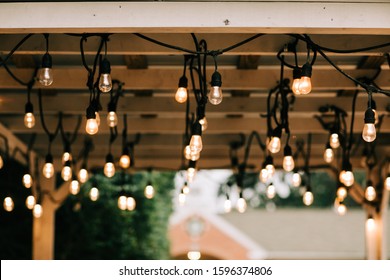 Hanging Vintage String Lights W On A Wooden Pergola Beams Patio In A Backyardith Edison Bulbs 