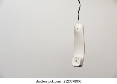 A Hanging White Handset Of An Outdated Home Phone