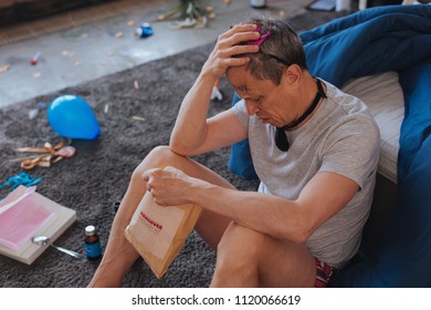 Hangover Symptoms. Top View Of Fatigued Mature Man Sitting On Floor And Studying Recovery Kit