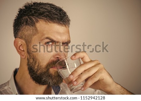 Hangover and thirst. Man with long beard hold water glass on grey background. Health and dieting. Hipster drink clean healthy water, refreshing. Life source and healthcare, copy space