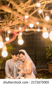 Hanoi City, Vietnam - December 2021: The Bride And Groom Are Happily Together In The Rooftop Garden Under The Romantic Shimmering Lights. The Photo Was Taken At Night.