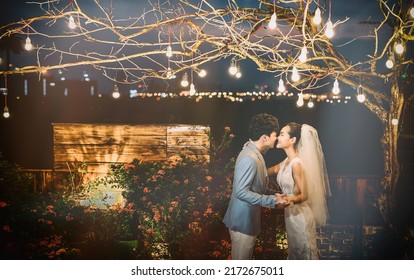 Hanoi City, Vietnam - December 2021: The Bride And Groom Are Happily Together In The Rooftop Garden Under The Romantic Shimmering Lights. The Photo Was Taken At Night.