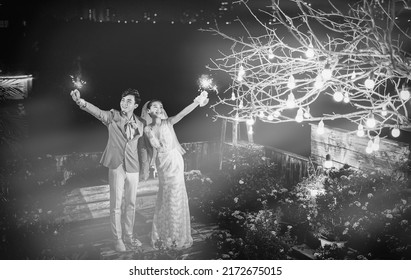 Hanoi City, Vietnam - December 2021: The Bride And Groom Are Happily Together In The Rooftop Garden Under The Romantic Shimmering Lights. The Photo Was Taken At Night.