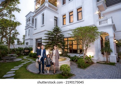 Hanoi City, Vietnam - December 2021: Happy Young Family Consisting Of Parents, Son And Daughter. Family Standing In Front Of Their Luxury Villa. Rich Asian Family.