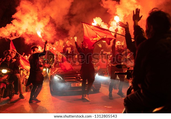 Hanoi, Vietnam - Dec 16,\
2018: Crowd of Vietnamese football fans down Hanoi street to\
celebrate the win after soccer, with a lot of Vietnamese flags\
raising high