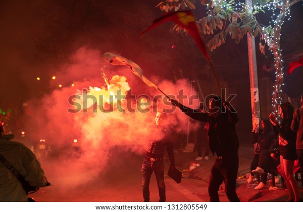 Hanoi, Vietnam - Dec 16,\
2018: Crowd of Vietnamese football fans down Hanoi street to\
celebrate the win after soccer, with a lot of Vietnamese flags\
raising high