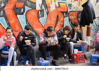 Hanoi, Vietnam - Feb 28, 2016: Customers have their meal on the street stall. Vietnamese people love to eat delicious food on sidewalk