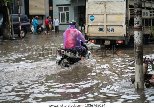 Hanoi, Vietnam - July 17, 2017: Flooded Minh Khai\
street after heavy rain with motorcycles and cars crossing deep\
water in Hanoi city,\
Vietnam