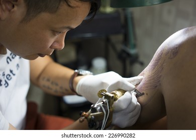 Hanoi, Vietnam - Oct 29, 2014: Tattoo Artist Makes A Tattoo On A Man Arm. Focus On Artist Face.