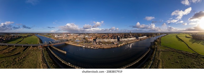 Hanseatic medieval city seen from across the river IJssel passing the white countenance facades on the boulevard. Aerial cityscape of tower town Zutphen. - Shutterstock ID 2083857919