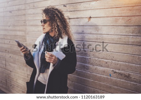 Hansome young woman hipster searching information in mobile network by smart phone, during walking in european city. Bokeh and flares effects on blurred background