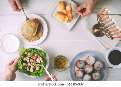 Hanukkah Dinner With Traditional Dishes On The White Wooden Table