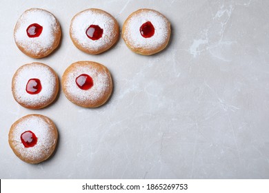 Hanukkah doughnuts with jelly and sugar powder on grey table, flat lay. Space for text