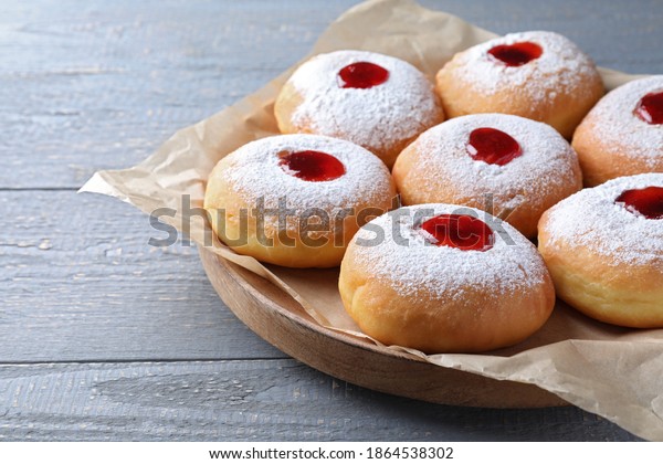 Hanukkah doughnuts with jelly and sugar powder on\
grey wooden table,\
closeup