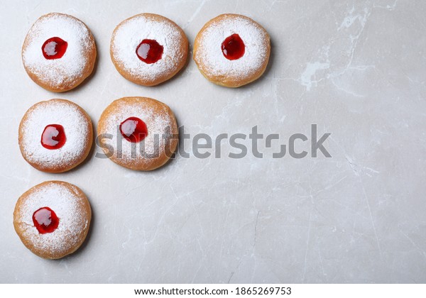 Hanukkah doughnuts with jelly and sugar\
powder on grey table, flat lay. Space for\
text