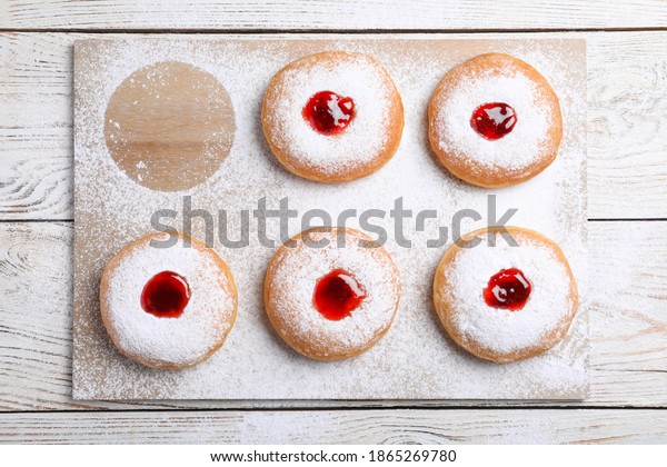 Hanukkah doughnuts with jelly and sugar powder on\
wooden table, flat lay