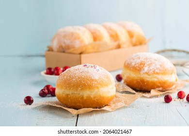 Hanukkah sweet food doughnuts sufganiyot with powdered sugar and fruit jam on blue wooden background. Jewish holiday Hanukkah concept. 