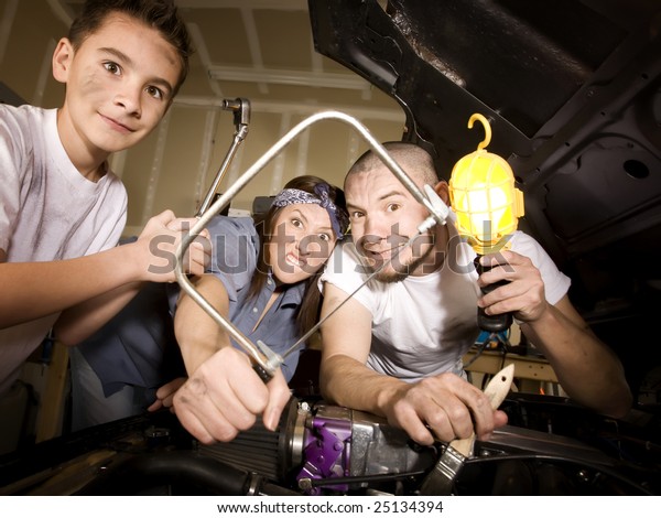 Hapless family of mechanics working on car with all\
the wrong tools