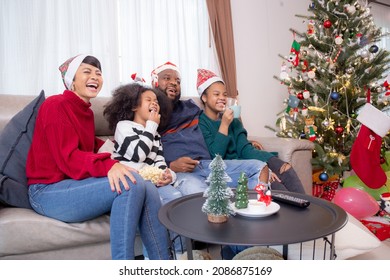 Happiness African Family Mom And Dad And Daughter Watching Tv And Laughing With Fun And Enjoyment In The Living Room At Home, Family Leisure With Television For Comfortable In Christmas Day.