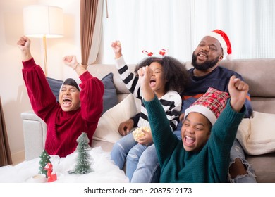 Happiness African family watching movie with excited and fun in the living room for leisure with comfort at home on Christmas day, dad and mom and daughter cheering watching tv with victory.