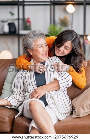 happiness asian family candid of daughter hug grandparent mother senior elder mom cozy relax on sofa couch in living room,Beautiful family of mother and daughter together, hugging and kissing at home Stock photo © 