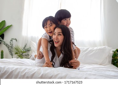 Happiness Of Asian Family With Mom And Son And Daughter Hug Mother On White Bed In Bedroom, Feeling Happy And Family Relationship Concept