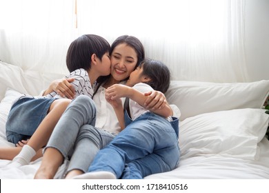 Happiness Of Asian Family With Mom And Son And Daughter Hug And Kissing Mother On White Bed In Bedroom, Feeling Happy And Family Relationship Concept