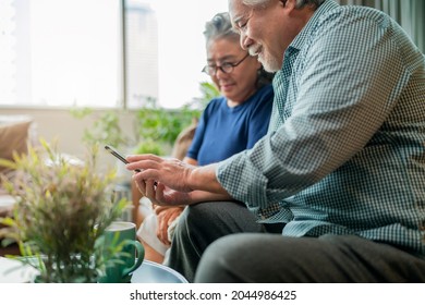 happiness asian old senior retired couple enjoy videocall to family together on sofa in living room at home,asian people use smartphone communication to family home isolation ides concept