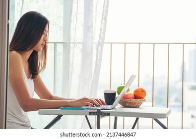 Happiness Asian Woman Working From Home Using Laptop Online Meeting In Home Office. Happy Relax Time Asian Business Woman Typing Keyboard Use Notebook Laptop Smiling, Laughing, Yawn At Home Office.