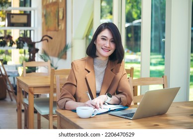 Happiness Asian Woman Working From Home Using Laptop Online Meeting In Home Office. Happy Relax Time Asian Business Woman Typing Keyboard Use Notebook Laptop Smiling, Laughing, Yawn At Home Office.