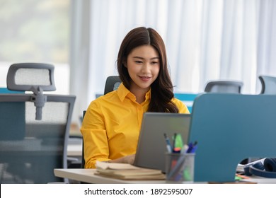 Happiness Attractive Asian woman in yellow shirt working with computer laptop thinking to get ideas and requirement in Business startup at modern office or Co-working space,Business Startup Concept - Shutterstock ID 1892595007