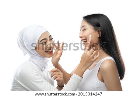 happiness of bestfriend laughing when applying face cream with finger hands against gray background