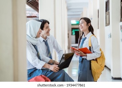 Happiness A Boy, Girl, And Girl In A Veil In High School Uniform Using A Laptop Computer Together When Discussing