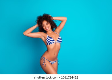 Happiness careless  people vacation concept. Pretty with beaming toothy smile beautiful cheerful excited afro woman clothed in striped swimwear is posing against bright blue background