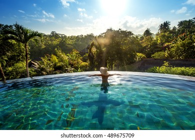 happiness concept. Woman sunbathing in infinity swimming pool at luxurious resort