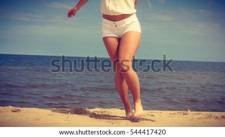 Young, slim woman on the beach of the Baltic Sea in summer wind