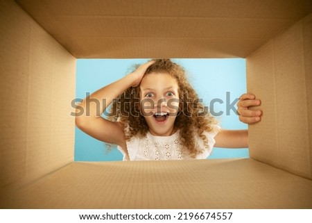Happiness, delight. Emotional kid, little girl looking inside box during opening, unpacking it. Delivery, surprise, gift, wow emotions concept. Black friday, holidays and online shopping