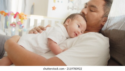 Happiness family Asian father enjoying resting time together caring cuddling embraces with adorable newborn baby girl lying on bed at home in the morning, Fatherhood family love relationship concept