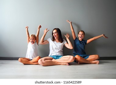 Happiness Family. Happy Mother And Excited Daughters Sitting In Living Room Wood Floor Raised Hands 