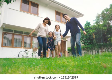 Happiness Family Play Together At Yard Outside Home. The Parents Smile With Their Daughters