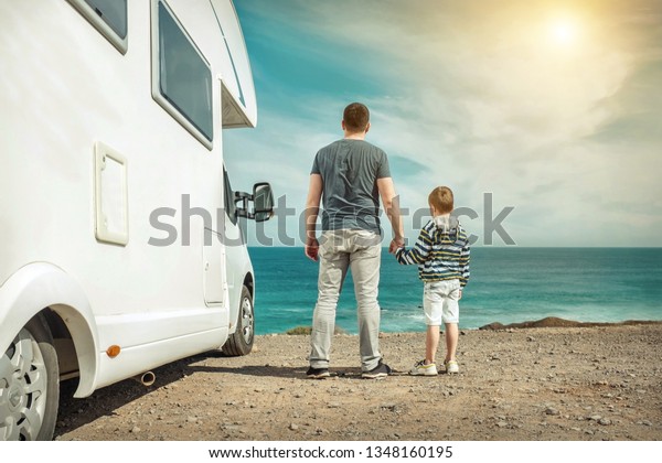 Happiness father\
and son, stay near them white travel car and look on the beautifull\
ocean coastline view in sunny day. Freedom, Family, Travell,\
Journej, Togetherness\
concept.