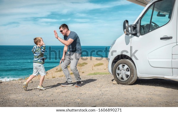 Happiness father\
and son, stay near them white travel car and look on the beautifull\
ocean coastline view in sunny day. Freedom, Family, Travell,\
Journej, Togetherness\
concept.