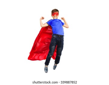 happiness, freedom, childhood, movement and people concept - boy in red super hero cape and mask flying in air